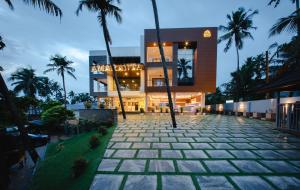 a building with palm trees in front of it at Hanric by Eight Continents Amaranta, Varkala in Varkala