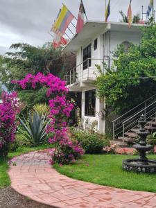a house with flags and flowers in front of a walkway at Telpochcalli Hotel & Temazcal in San Juan Teotihuacán
