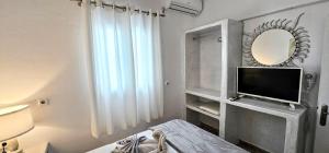 a living room with a television and a mirror at Santorini Studios Pleasure in Perissa