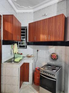 a kitchen with wooden cabinets and a stove top oven at Rippon Nest in Jinja