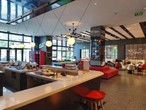 a restaurant with a bar with red chairs and tables at Ibis Haiyan Economic Development Zone in Haiyan