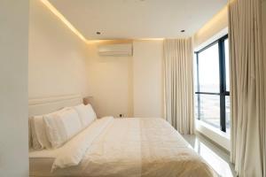 a white bedroom with a bed and a window at Beige Apartment by Bait Zain - Bousher in Muscat