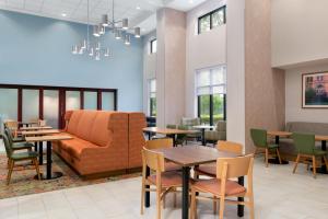 a waiting room with a couch and tables and chairs at Hampton Inn & Suites Prattville in Prattville