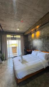 ein Schlafzimmer mit einem großen weißen Bett und einer Betonwand in der Unterkunft Lungga in General Luna + 34 Fotos