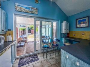 a kitchen with blue walls and a table and chairs at Penny Cottage in Heacham