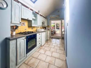 a kitchen with white cabinets and a tile floor at Penny Cottage in Heacham