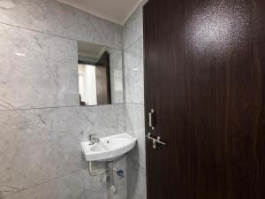 a bathroom with a sink and a wooden door at Hotel Dwarka Executive in Nashik