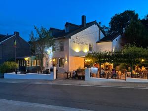 people sitting at tables outside of a building at Hotel Restaurant The Kings Head Inn in Voeren