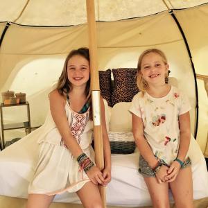 two girls sitting on a bed with umbrellas at Harmony Glamping Boutique Hotel and Yoga in Tulum