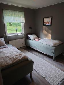 a bedroom with two beds and a window at Stuga vad vatten in Åsarp