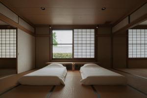 two beds in a room with two windows at o ku in Awaji