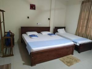 two twin beds in a room withthritisthritislictslictslicts at Under Water Safaris and Resort in Trincomalee