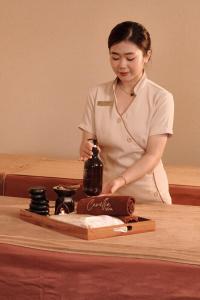 a woman is standing at a table with a bottle at The IRIS SIGNATURE HOTEL AND SPA in Can Tho +85 photos