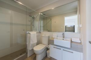 a bathroom with a toilet and a sink and a mirror at 9 by the Beach in Rockingham +52 photos
