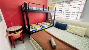 a bedroom with two bunk beds and a chair at Bidara Guest House in Kampong Sungai Baru Tengah