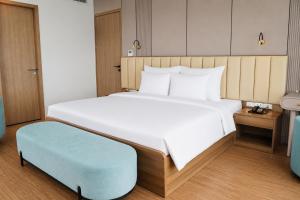 a bedroom with a large bed and a blue ottoman at The Golden Crest Hotel Quy Nhon in Quy Nhon