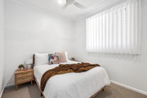 a bedroom with a bed with a brown blanket on it at Coolum Beach Apartment, 2 Bed 2 Bath, Pool in Coolum Beach +6 photos