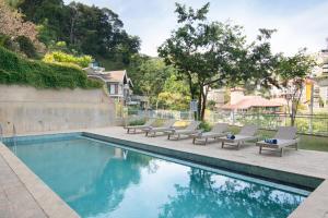 a swimming pool with chaises and chairs next to at Oak Ray Sky Terrace in Kandy