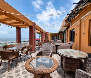 an outdoor patio with tables and chairs and the ocean at Hotel Big Boss New Digha in Digha