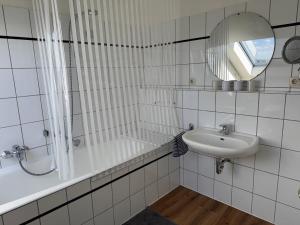 a white tiled bathroom with a sink and a shower at Fewo Bad Salzuflen in Bad Salzuflen +16 photos