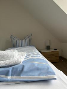 a bed with a blue blanket and a night stand at Gästehaus St Markus in Höxter