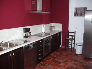 ベルモンテにあるCasa Rural Descanso del Quijoteの赤い壁のキッチン(シンク、冷蔵庫付)