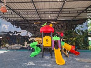 a playground with different colored slides in front of a wall at Chill Hutz in Vedakudiyiruppu