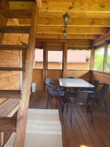 a wooden cabin with a table and chairs on a deck at Ojcowizna na Kresach in Jurowlany