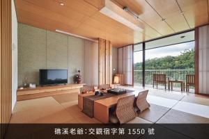 a living room with a television and a table and chairs at Hotel Royal Chiao Hsi in Jiaoxi