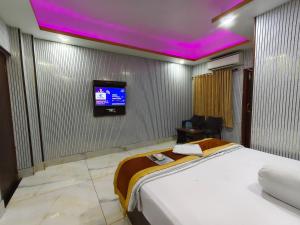 a bedroom with a bed and a tv on the wall at ICONIC Hotel Digha in Digha