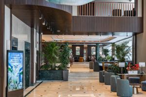 a lobby with chairs and plants in a building at Radisson Blu Hotel, Tashkent in Tashkent +117 photos