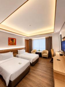 a hotel room with two beds and a television at Orchardz Hotel Industri Jakarta Kemayoran in Jakarta