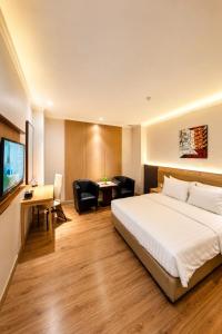 a hotel room with a bed and a desk and chair at Orchardz Hotel Industri Jakarta Kemayoran in Jakarta