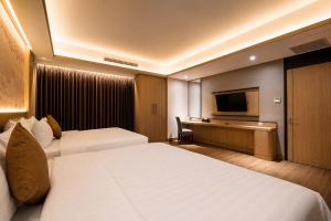 a hotel room with two beds and a flat screen tv at Orchardz Hotel Industri Jakarta Kemayoran in Jakarta
