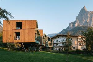 a building with a wooden facade on a grass field at Floris Green Suites by Parc Hotel Florian in Siusi