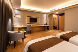 a hotel room with two beds and a desk at Orchardz Hotel Industri Jakarta Kemayoran in Jakarta