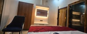 a bedroom with a bed and a chair and a television at The Eros in Sonīpat