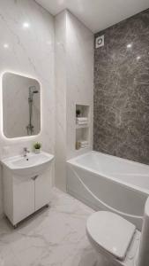 a white bathroom with a tub and a sink and a toilet at Алпамыс - В пешей доступности Центральный парк, ЦУМ, ТРЦ MART in Kostanay +32 photos
