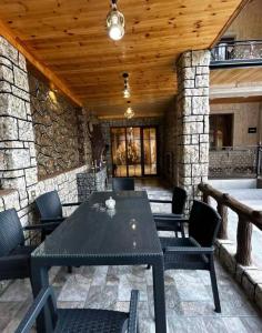 a patio with a table and chairs and a stone wall at Yusubovs in Hacıkǝnd