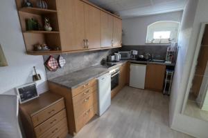 a small kitchen with wooden cabinets and white appliances at NEU! Ferienwohnung am Schanzenbach in Hartha