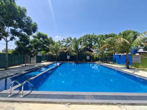 a blue swimming pool with palm trees in the background at Chill Hutz in Vedakudiyiruppu +20 photos