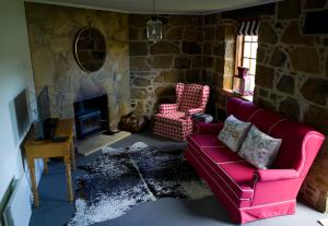 a living room with a red couch and a stone fireplace at The Storekeeper's in Buckland