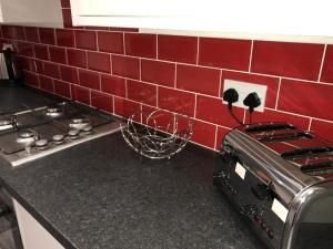 a kitchen counter with a stove and red tiles at JO Wordsworth Apartment in Hull