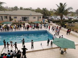a group of people standing around a swimming pool at Floyds Beach Resort & Spa in Nyanyanu
