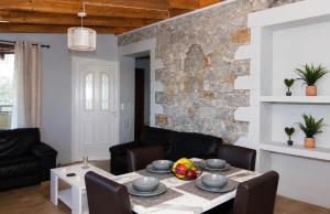a living room with a table and a stone wall at Emilia's Guest House with Sea View Balcony, Stoupa in Stoupa +14 photos