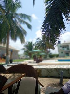 a table and chairs on a patio with palm trees at Floyds Beach Resort & Spa in Nyanyanu +1 photo