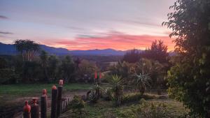 a sunset over a garden with palm trees and mountains at Kairos Vista in Sedgefield