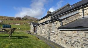 a stone house with a picnic table in front of it at Ty Llugwy in Betws-y-coed
