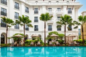 a swimming pool in front of a building with palm trees at Avani Plus Lanexang Vientiane Hotel in Vientiane