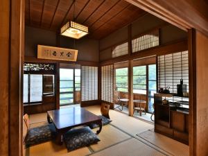 a living room with a table and chairs and windows at Masuya Ryokan in Aoki